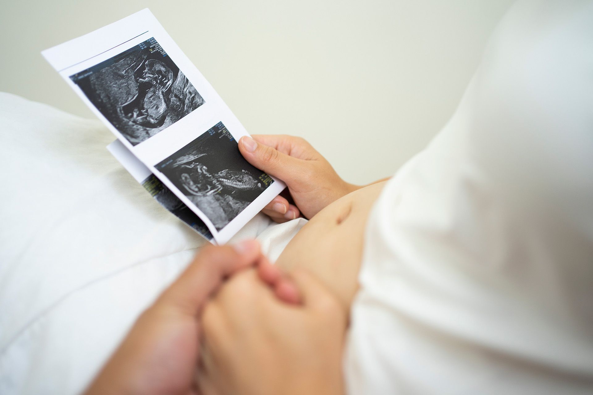 A pregnant woman is looking at an ultrasound of her baby