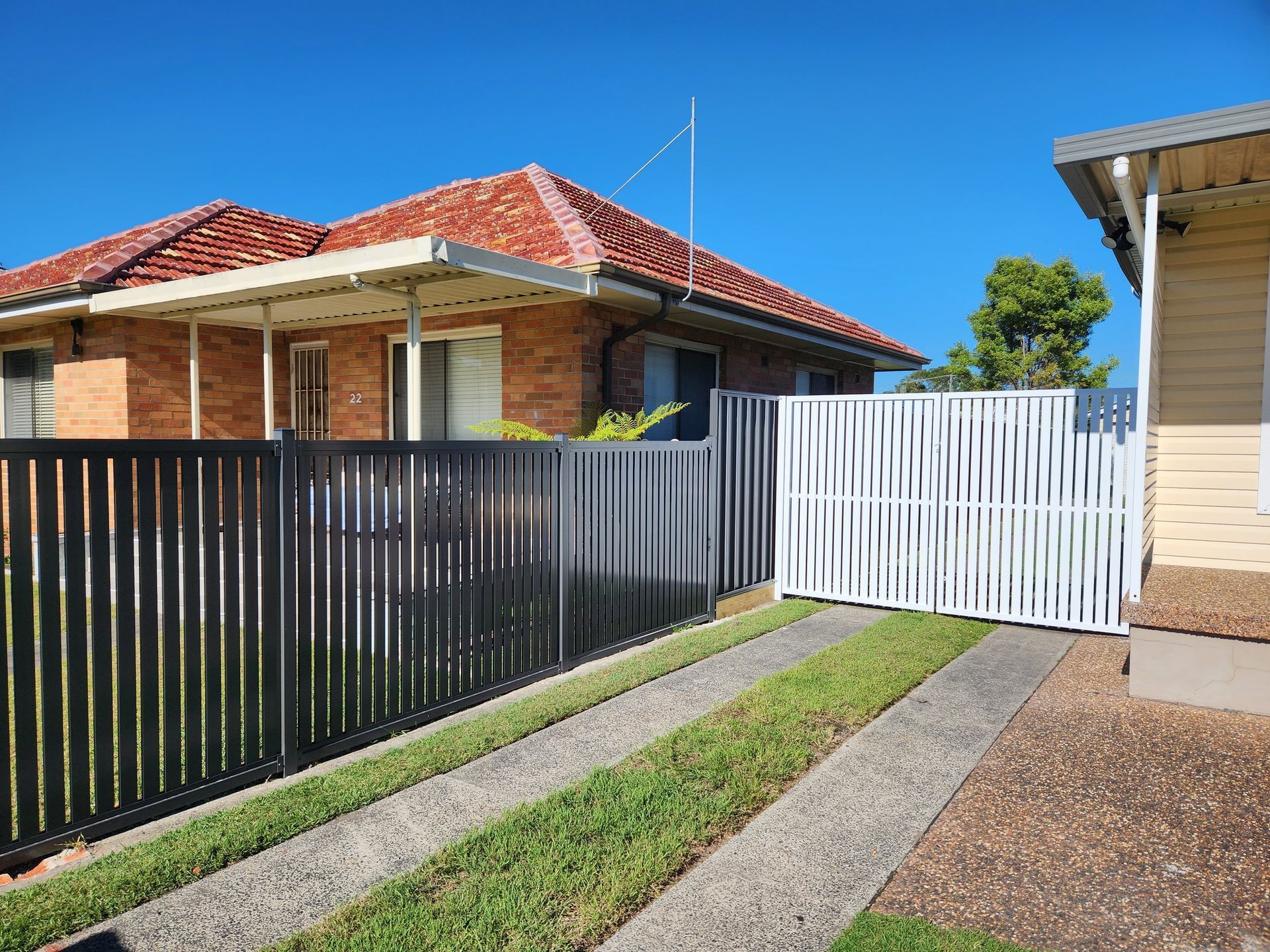 A house with a black fence and a white gate in front of it.