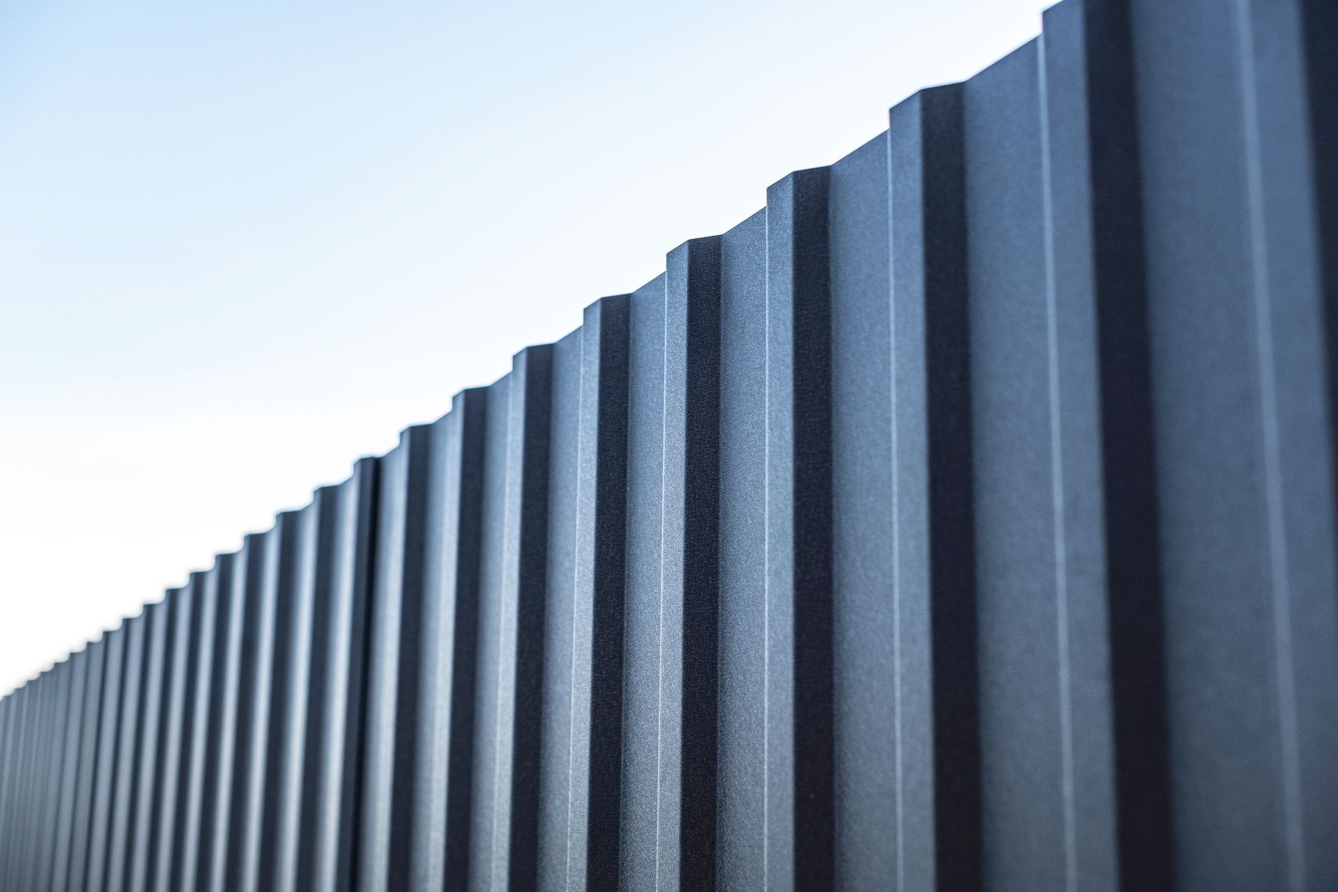 A close up of a black metal fence with a blue sky in the background.