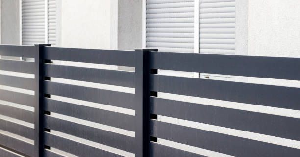 A black fence with white stripes is in front of a window.