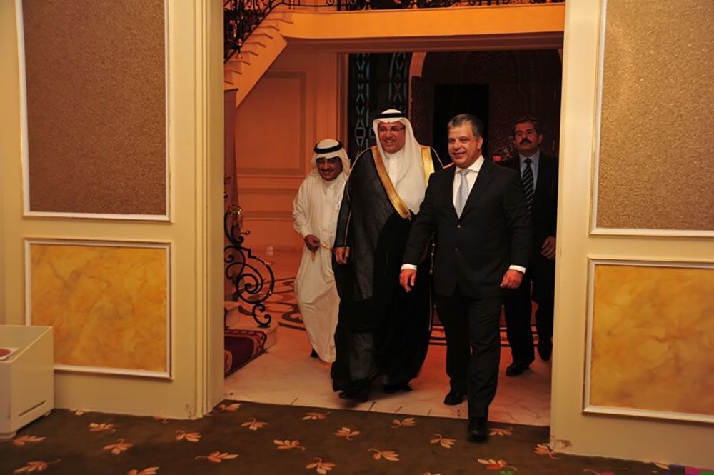 Men in formal attire walk through a doorway in a luxurious building.