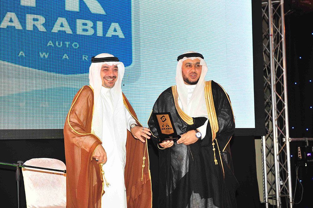 Two men in traditional Arab dress holding a plaque, at an award ceremony.
