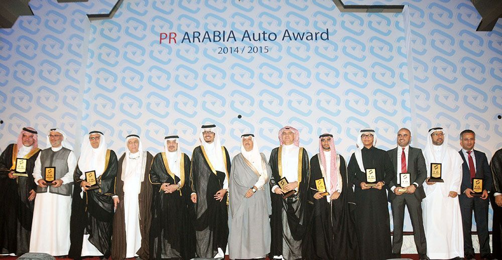 People in formal attire holding awards at the PR Arabia Auto Award ceremony.
