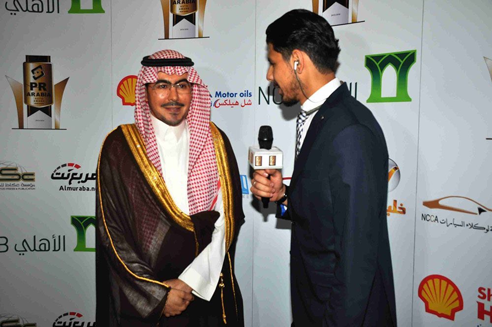 Man in traditional Saudi attire being interviewed at an event.