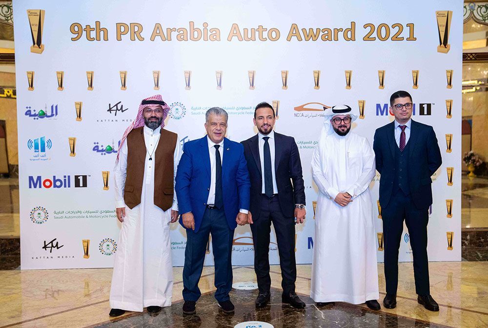 Men at the 9th PR Arabia Auto Award 2021. Five men stand in front of a branded backdrop.