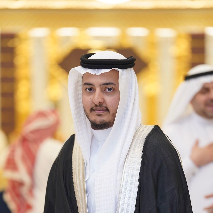 Man in traditional Arab attire, smiling. Indoors with blurred background.