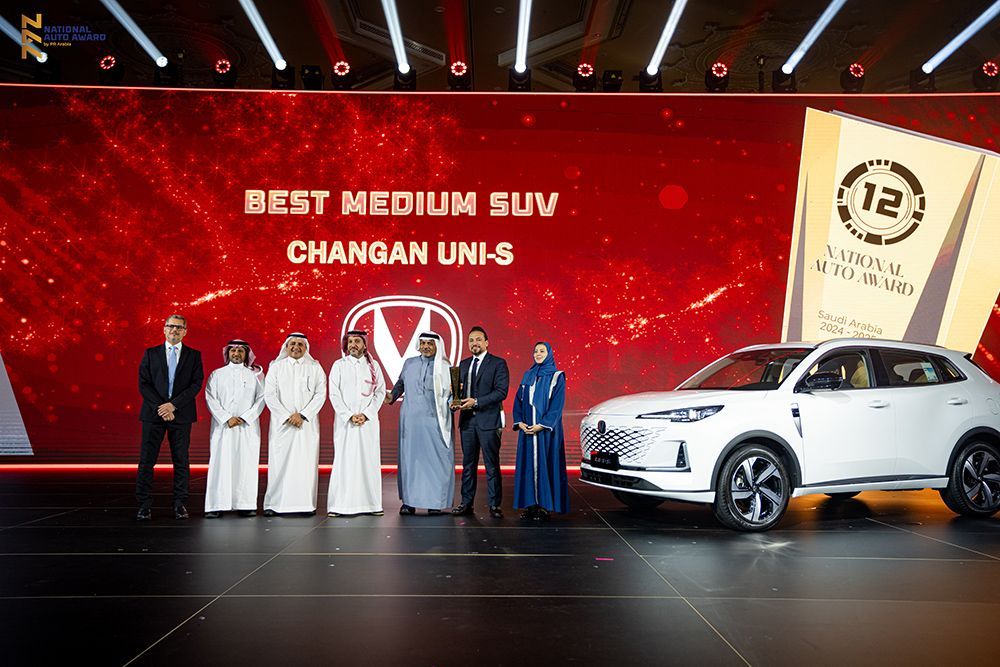 Award ceremony with people on stage; a white Changan Uni-5 SUV, and a red backdrop that says 