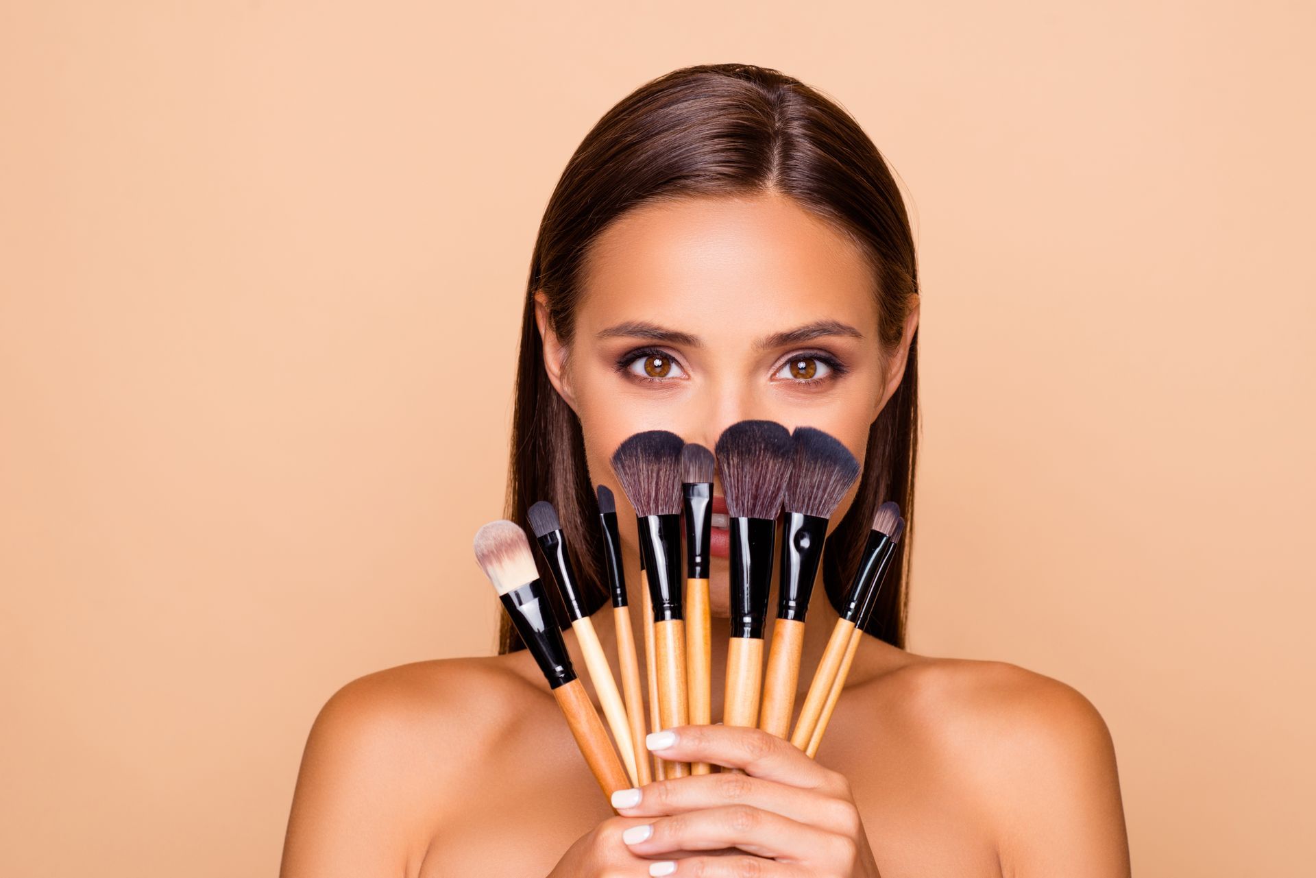 Eine Frau hält einen Stapel Make-up-Pinsel vor ihr Gesicht.