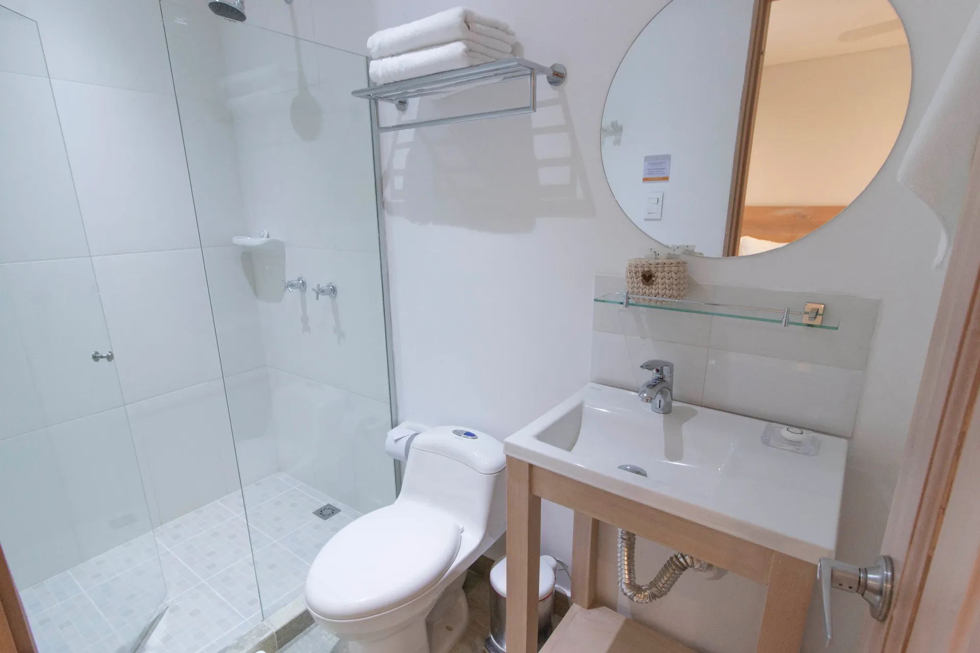 Un baño con inodoro, lavabo, ducha y espejo.