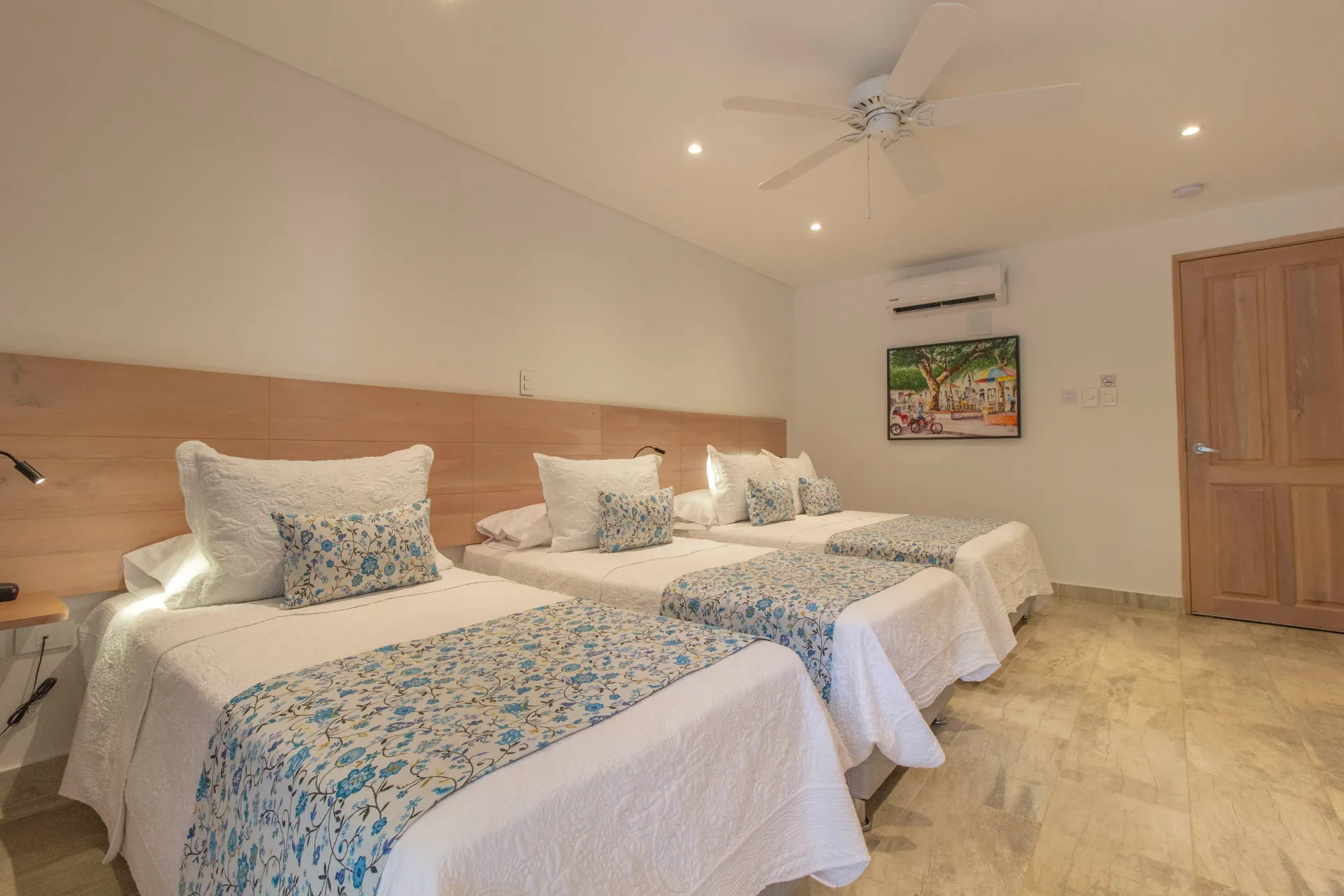 Una habitación de hotel con tres camas y un ventilador de techo.