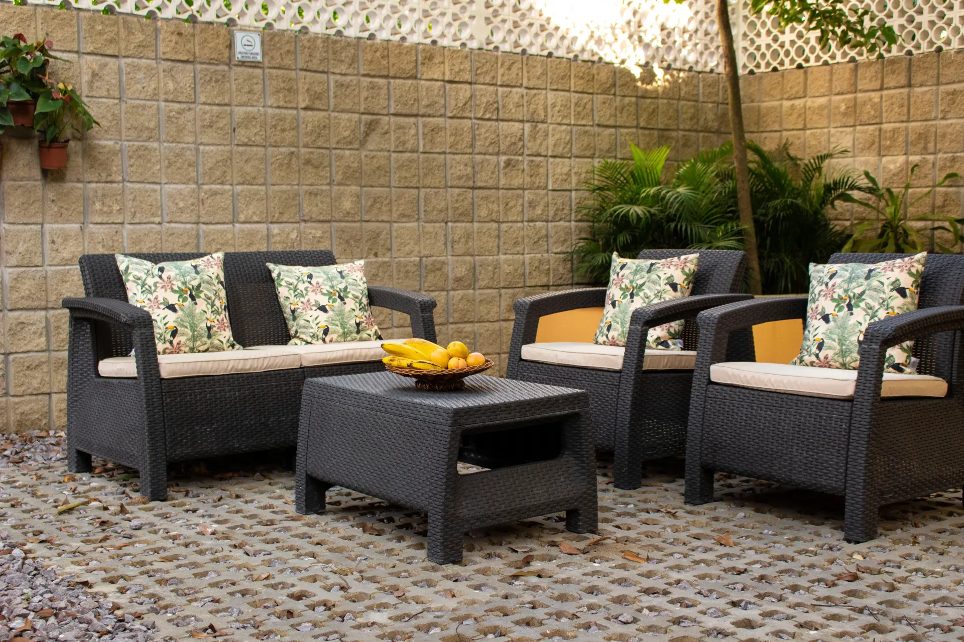 A patio with wicker furniture and a table with a bowl of bananas on it.