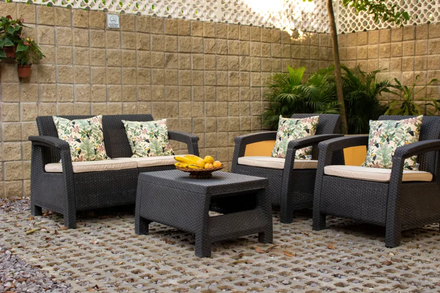 Un patio con muebles de mimbre y una mesa con un bol de plátanos encima.