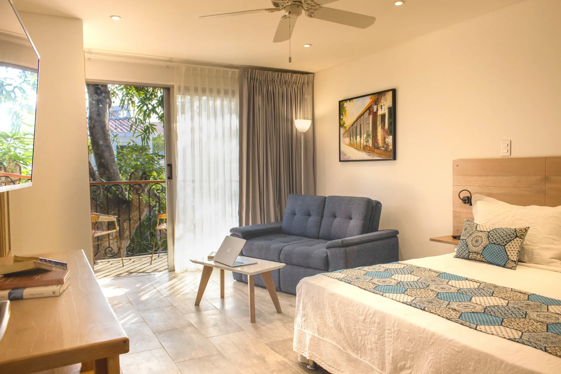 Una habitación de hotel con cama, sofá, mesa y ventilador de techo.