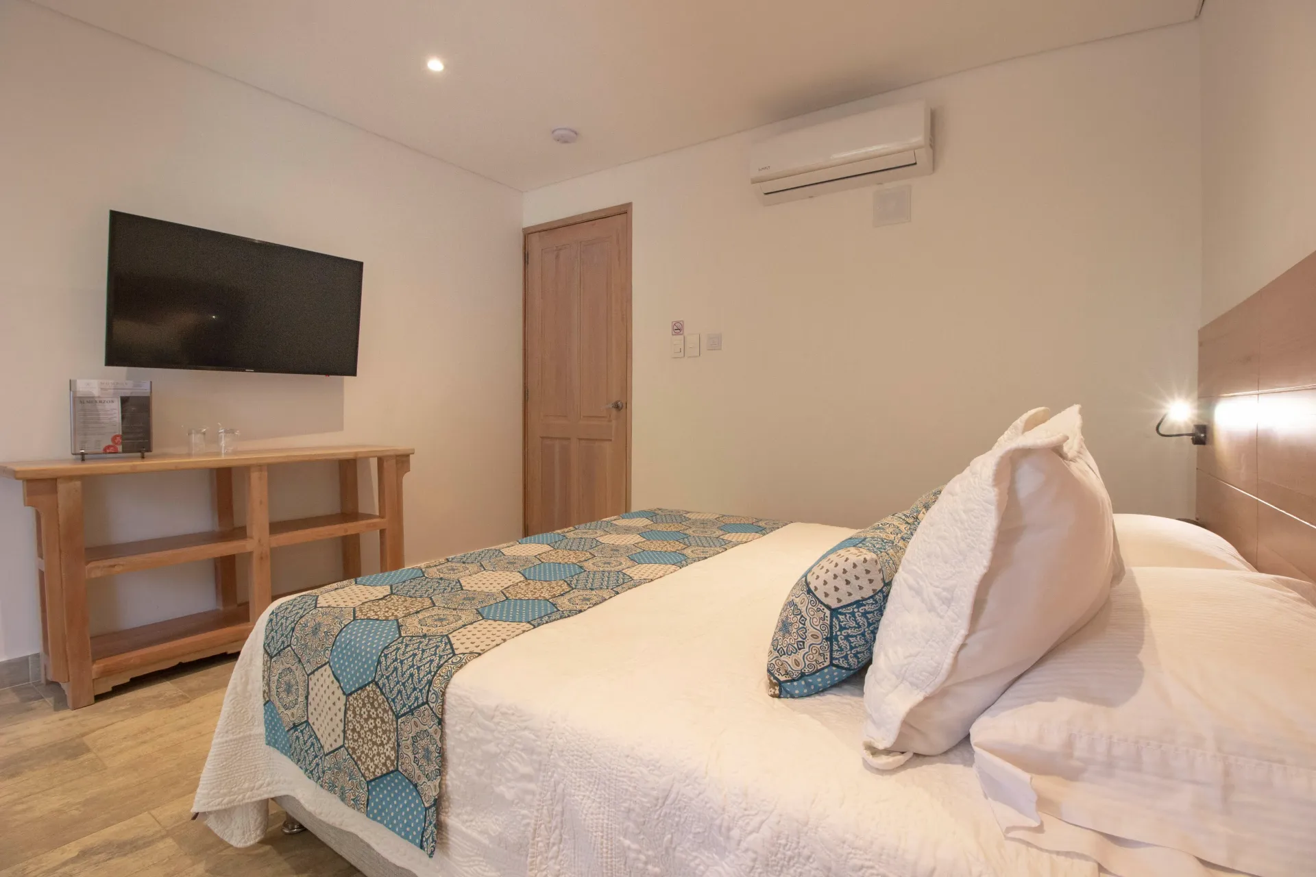 Una habitación de hotel con cama, televisión y aire acondicionado.
