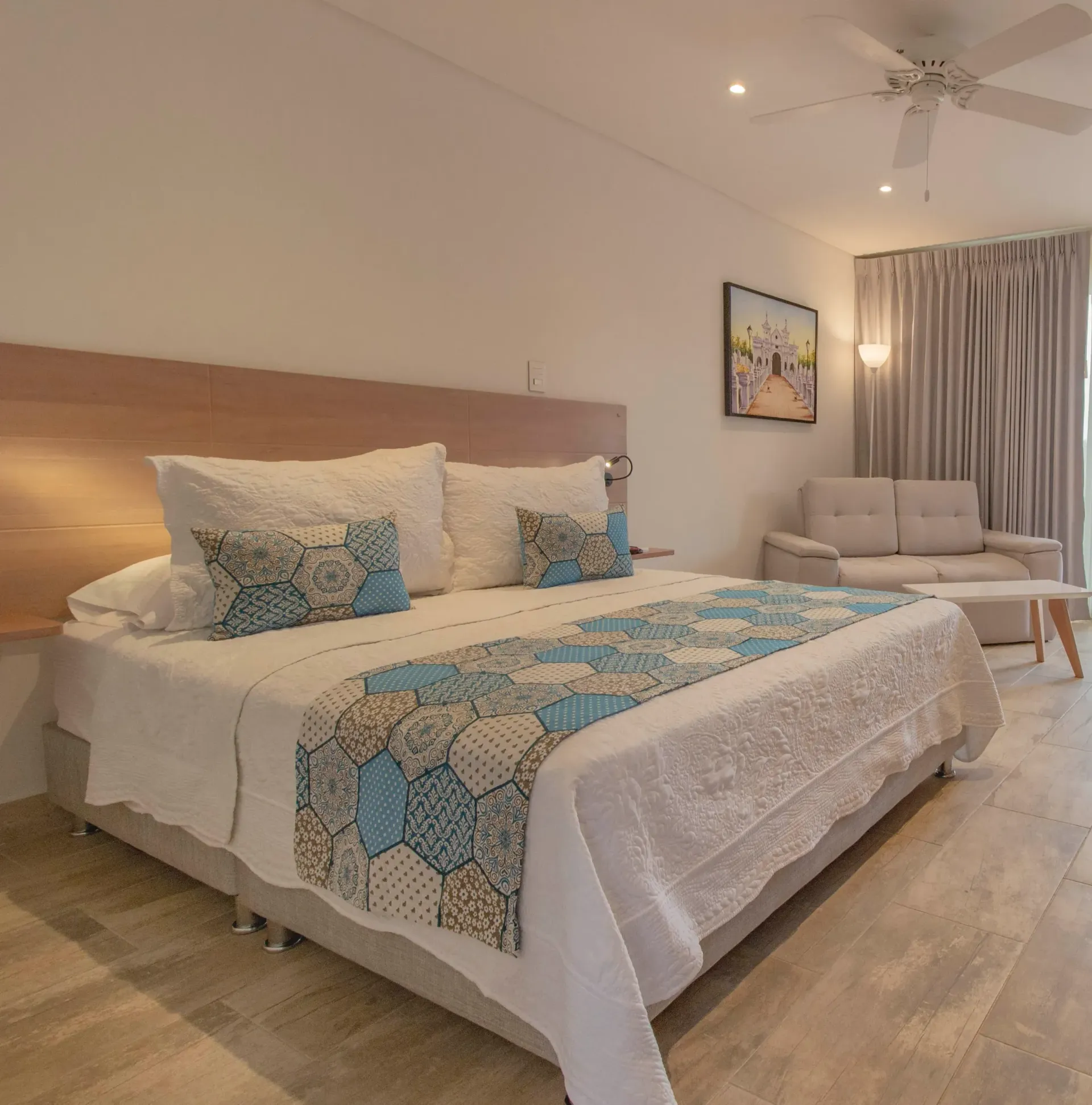 A hotel room with a king size bed and a ceiling fan