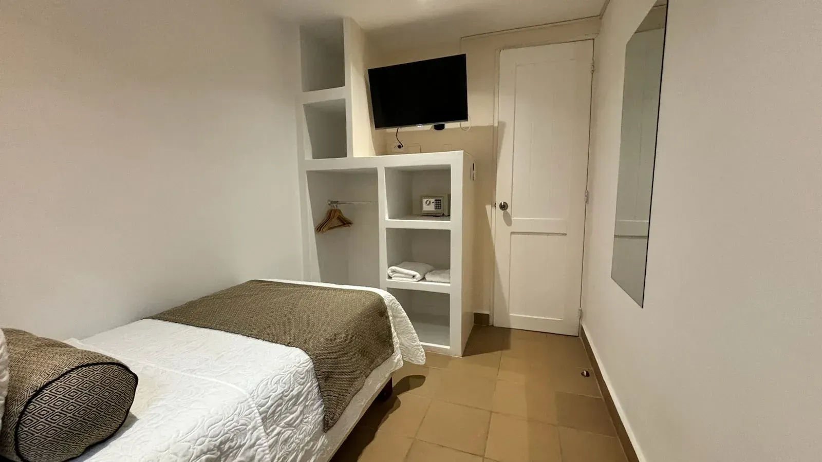 Un dormitorio pequeño con una cama individual y un televisor de pantalla plana.