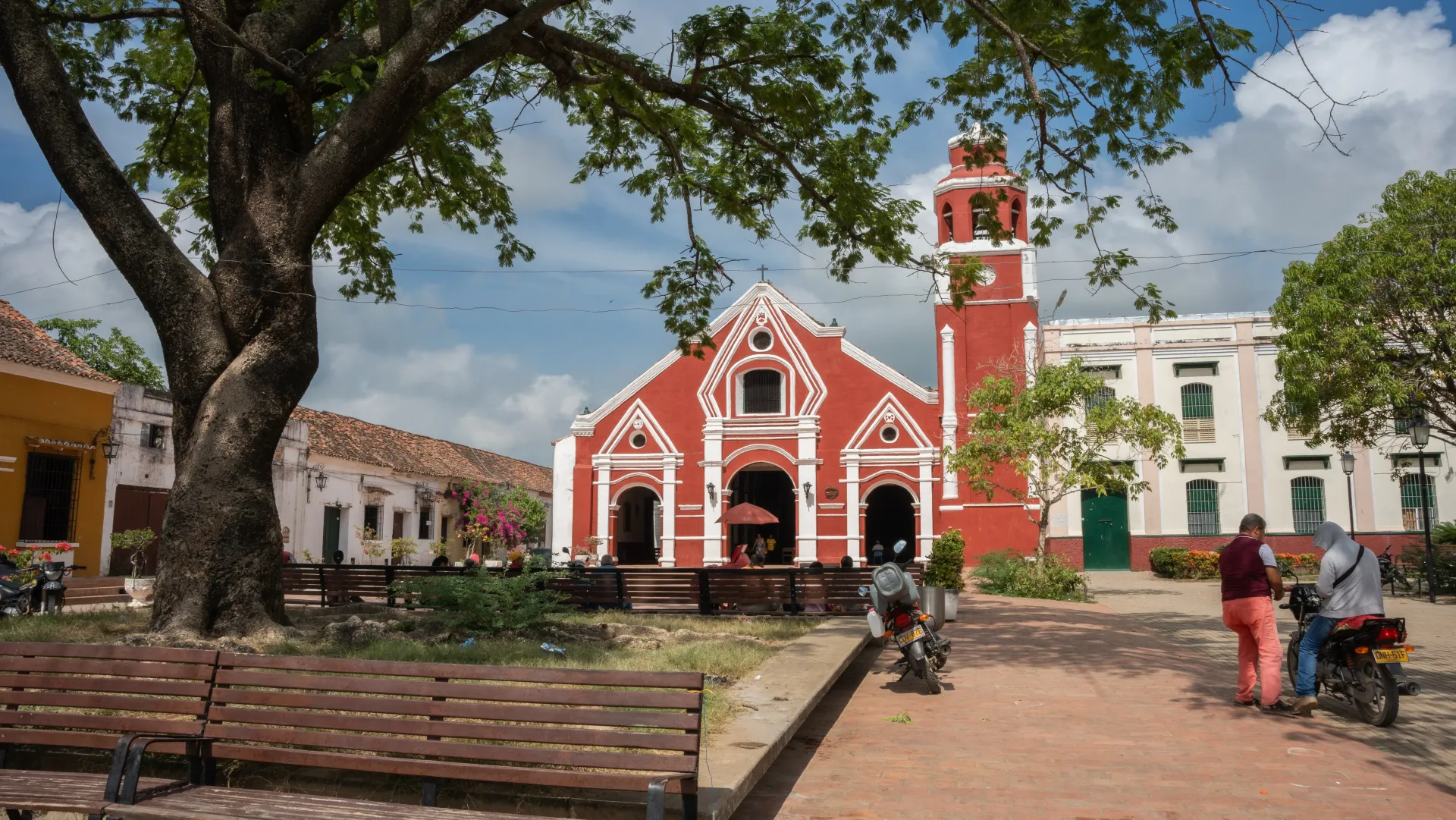 Un grupo de personas camina frente a una iglesia roja y blanca.