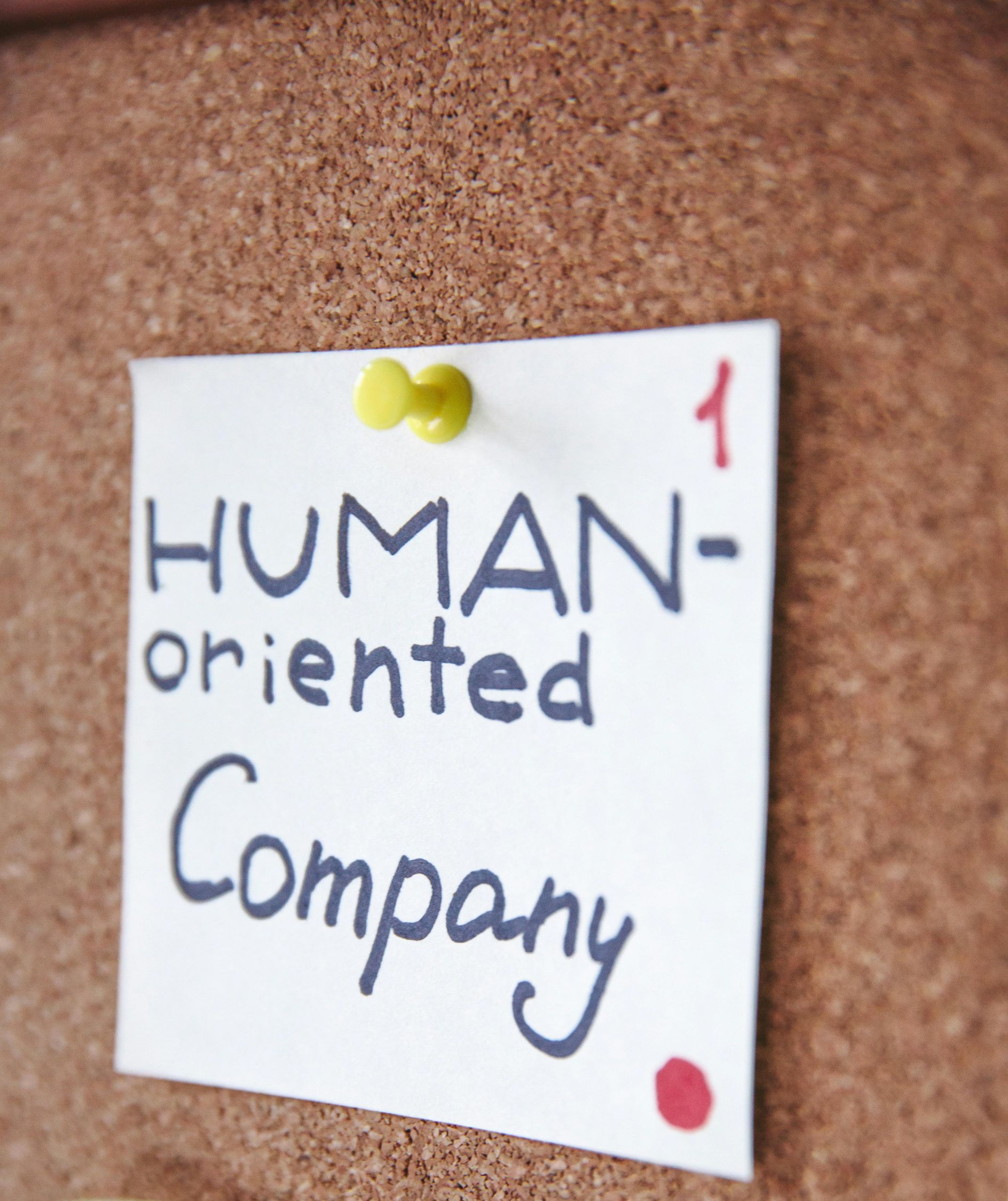 Un tablero de corcho tiene una nota fijada que dice empresa orientada al ser humano