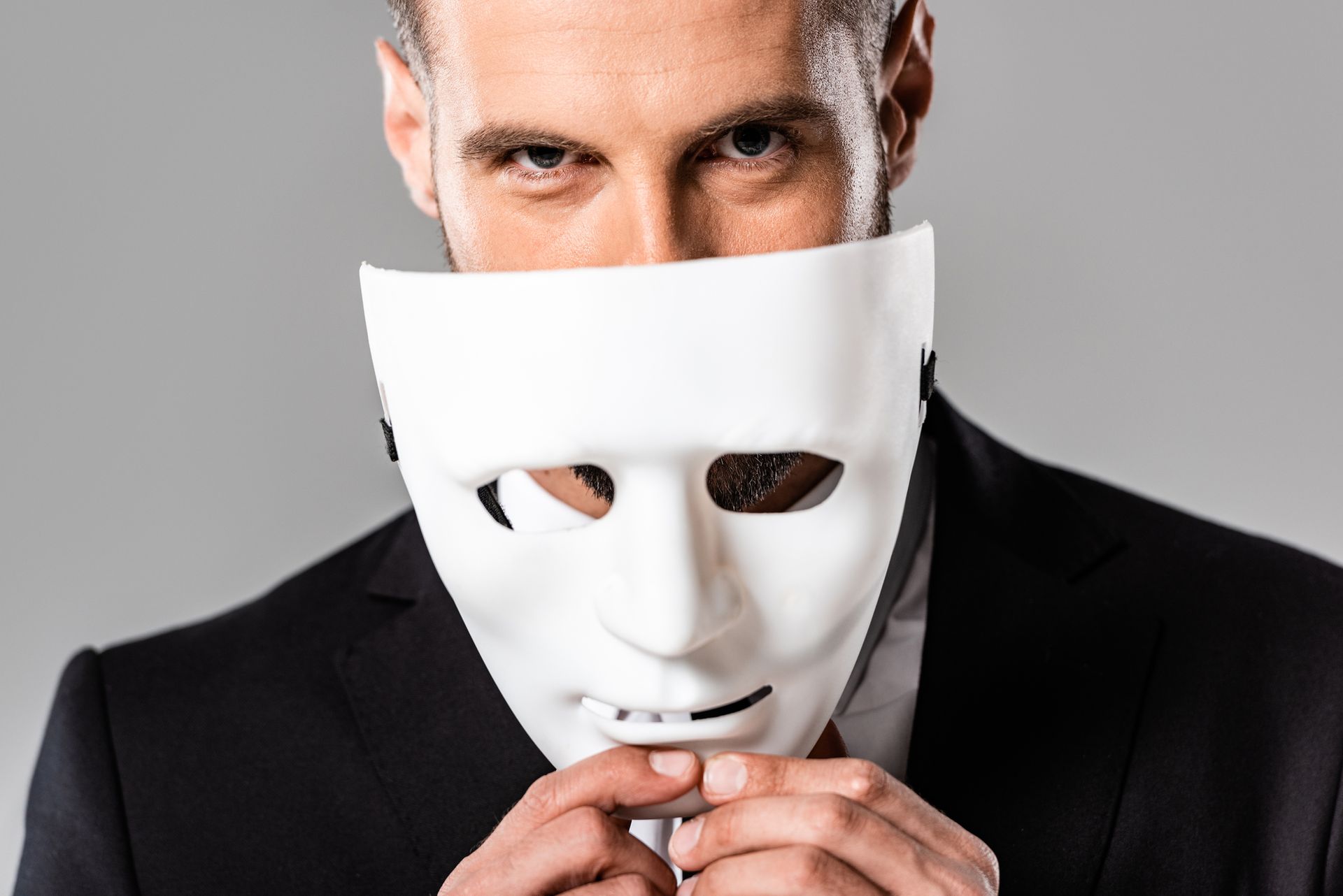 PTSS Voorbij-Holistisch herstel van PTSS en Trauma-Johan Reinhoudt-Spinnenweb Sluwe zakenman in zwart pak-met wit masker in zijn hand