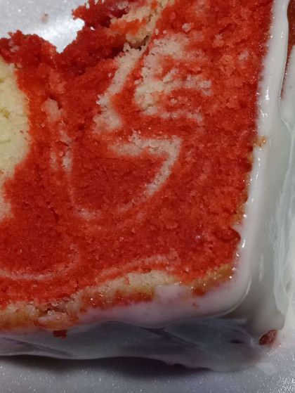 A slice of red velvet cake with white frosting on a white plate.