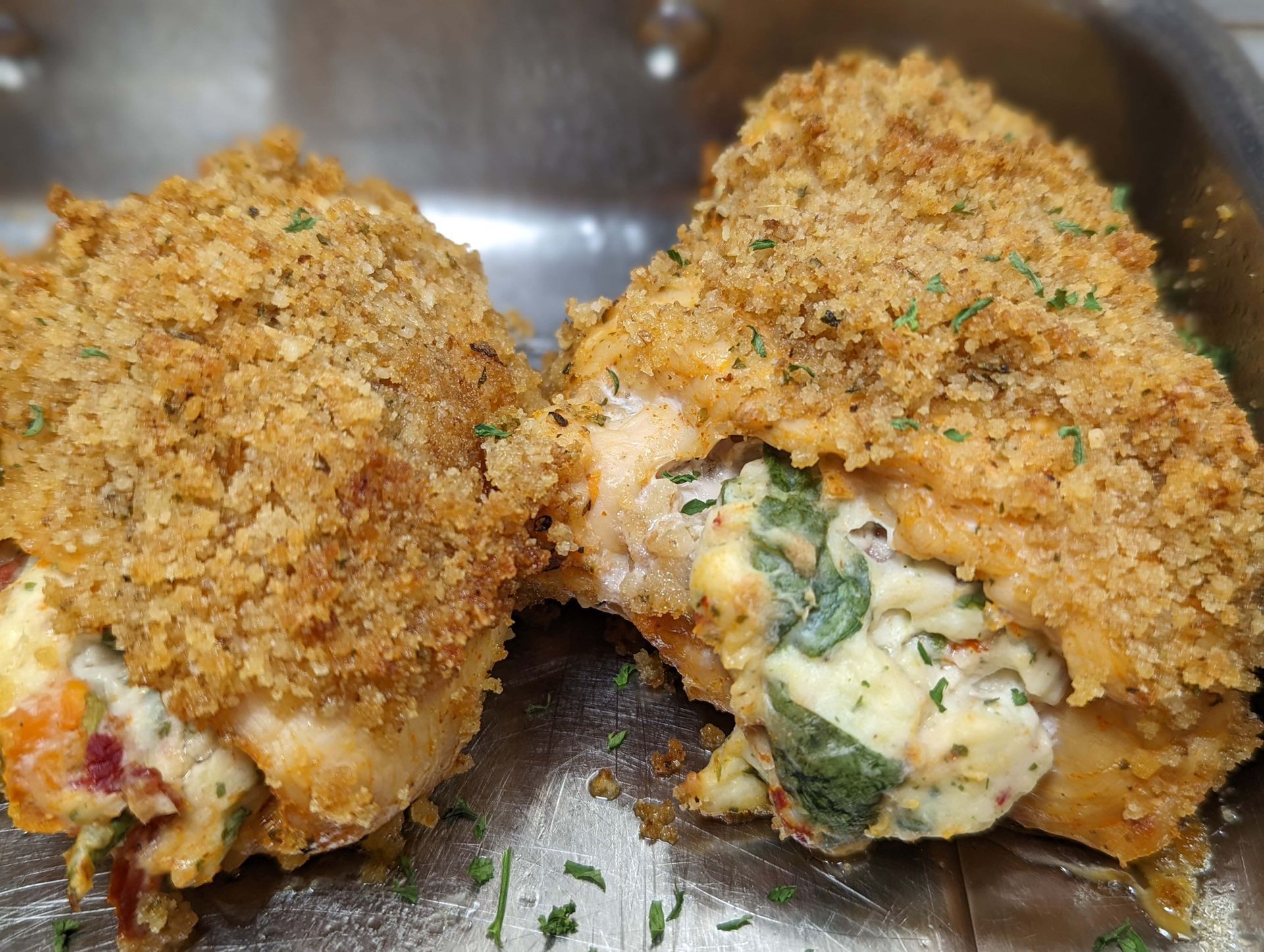 A close up of two stuffed chicken breasts on a plate.