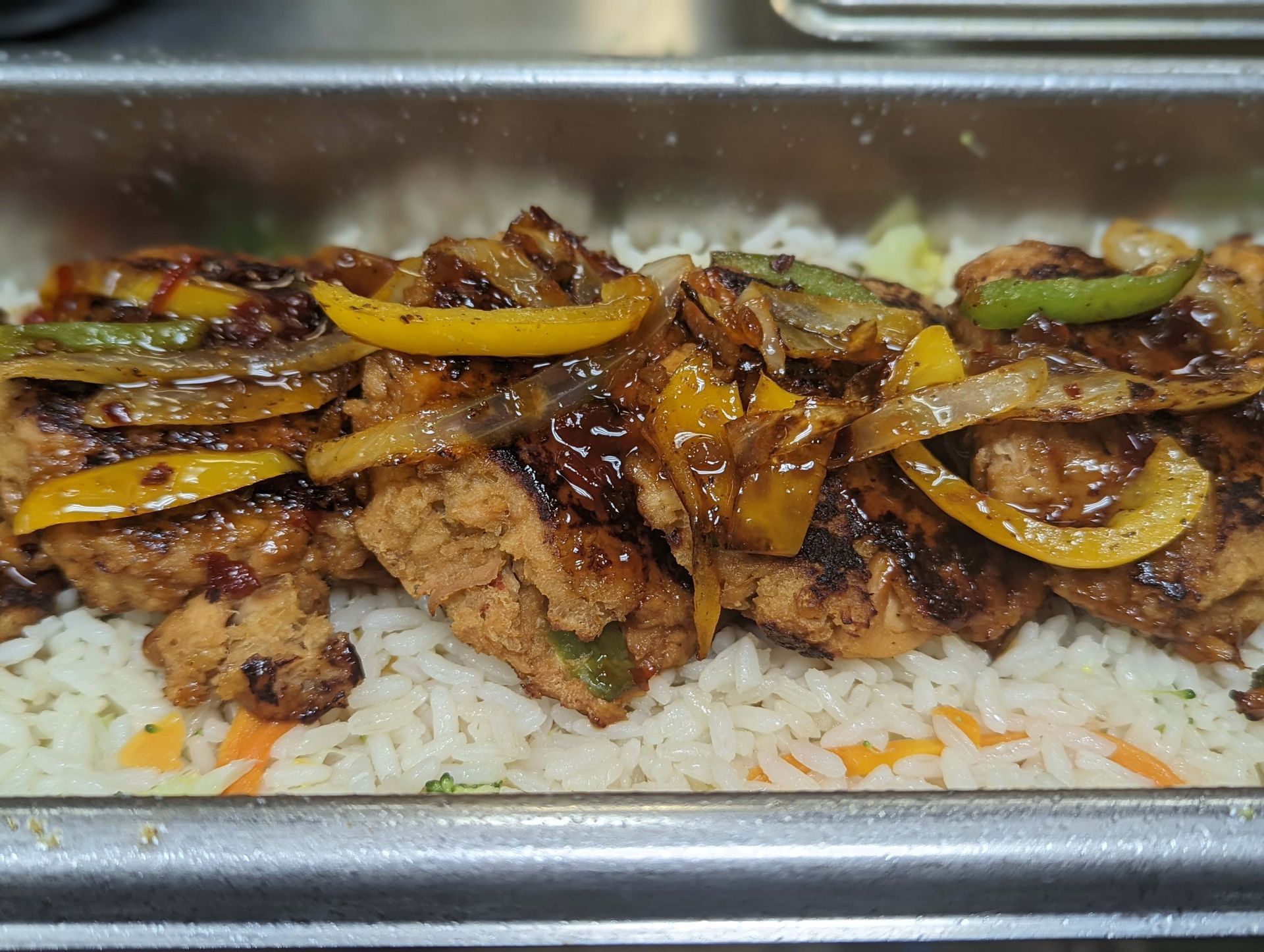 A close up of a tray of food with rice and meat on a table.