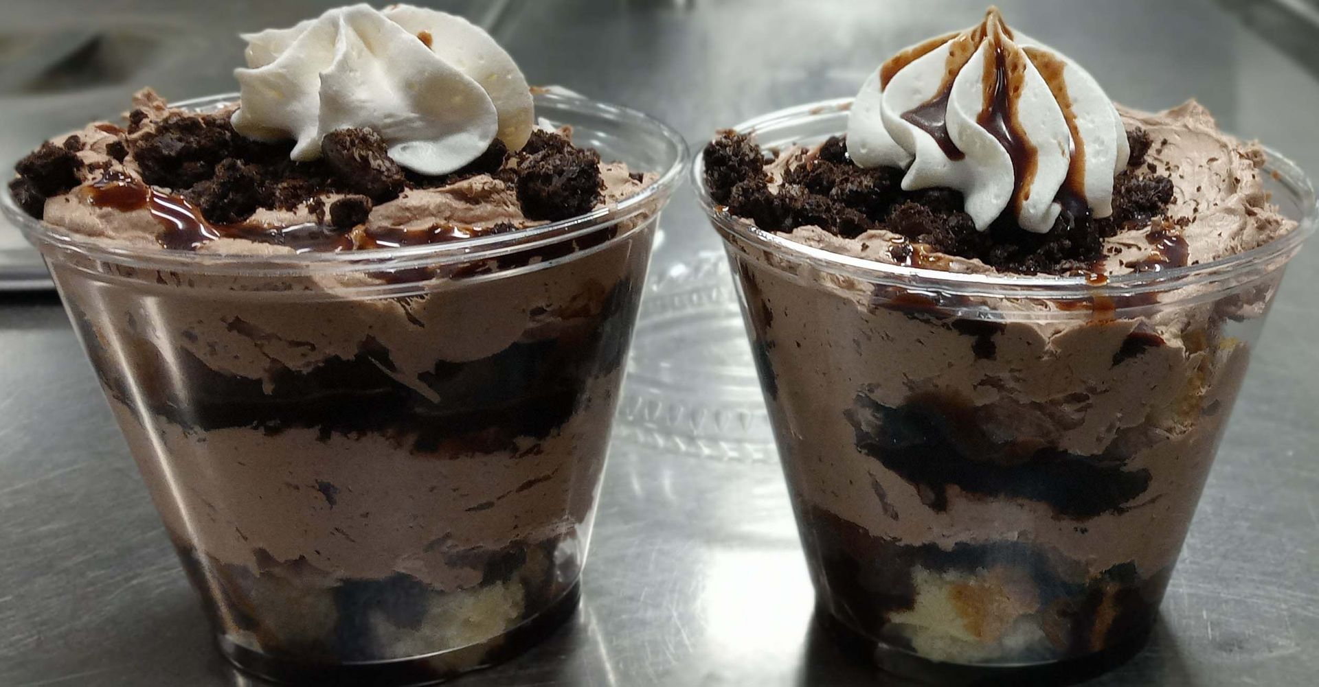 Two cups of dessert with whipped cream on top are sitting on a table.