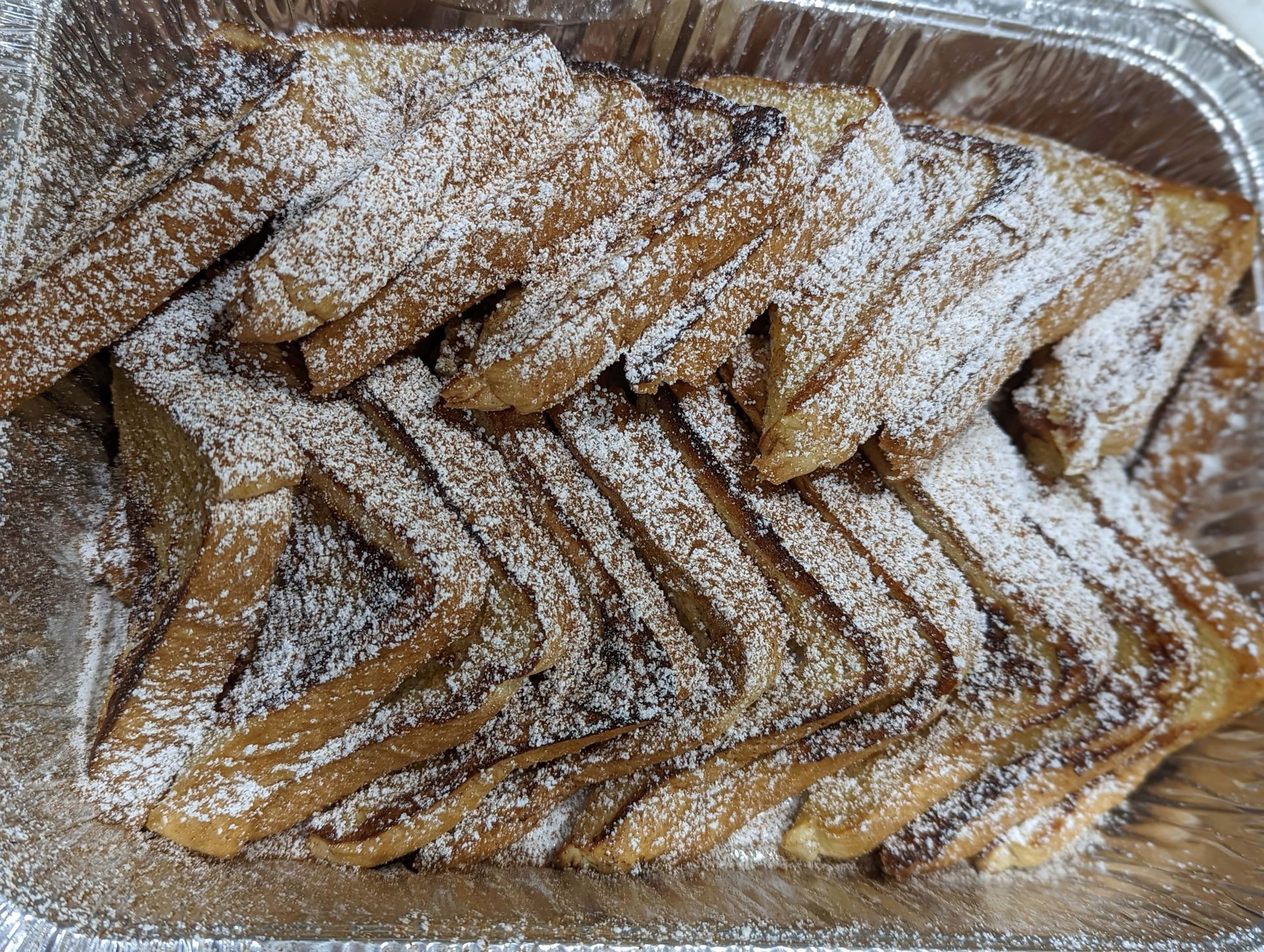 A tray of french toast with powdered sugar on top.
