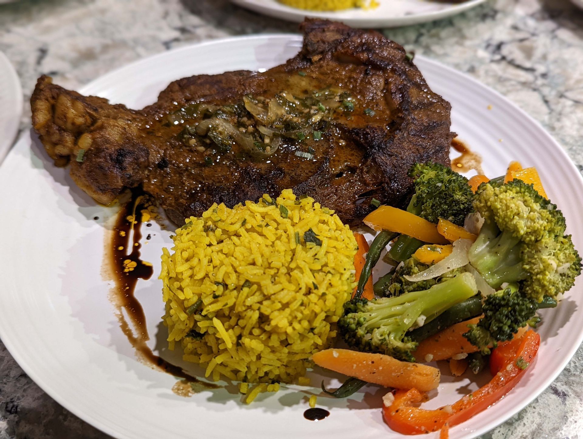 A white plate topped with a steak , broccoli , rice and vegetables.