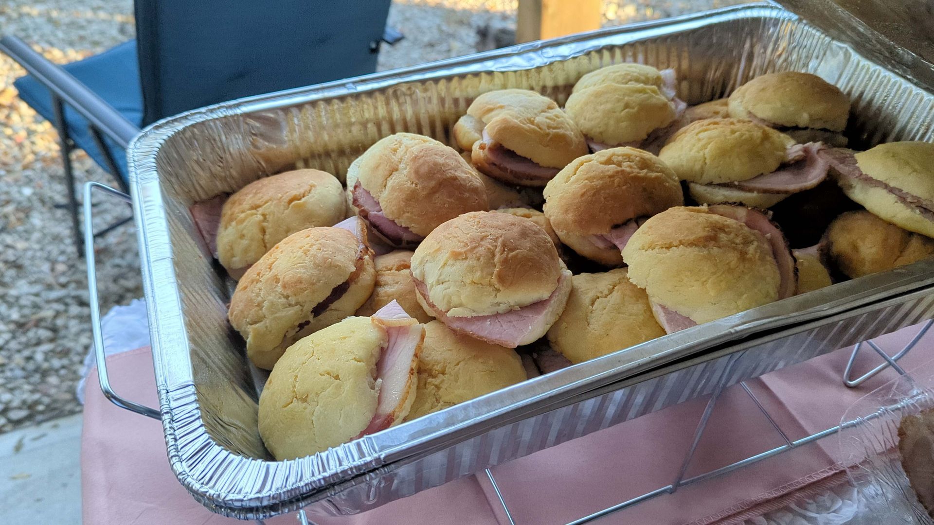 A tin foil container filled with sandwiches on a table.