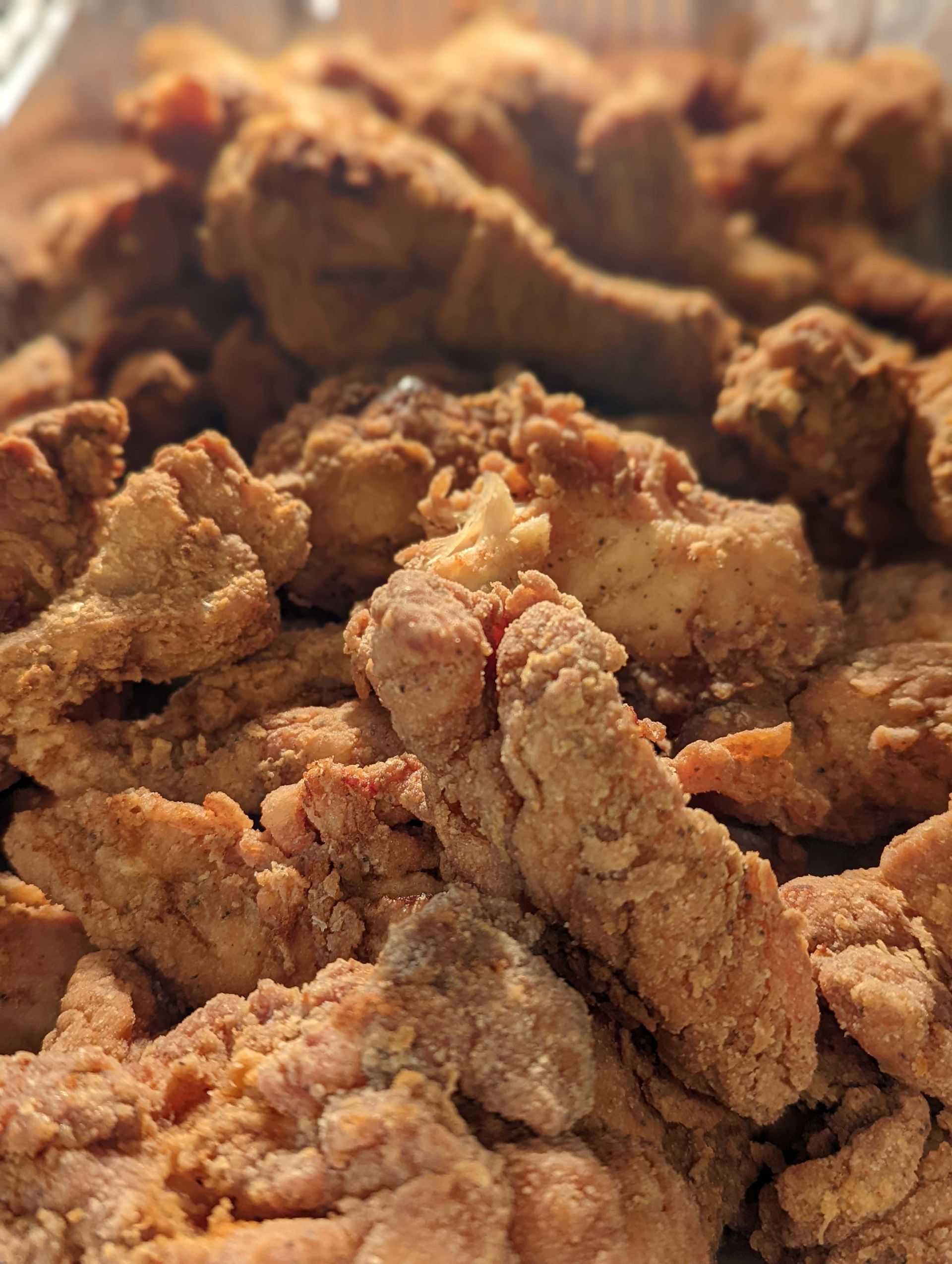 A close up of a pile of fried chicken in a plastic container.