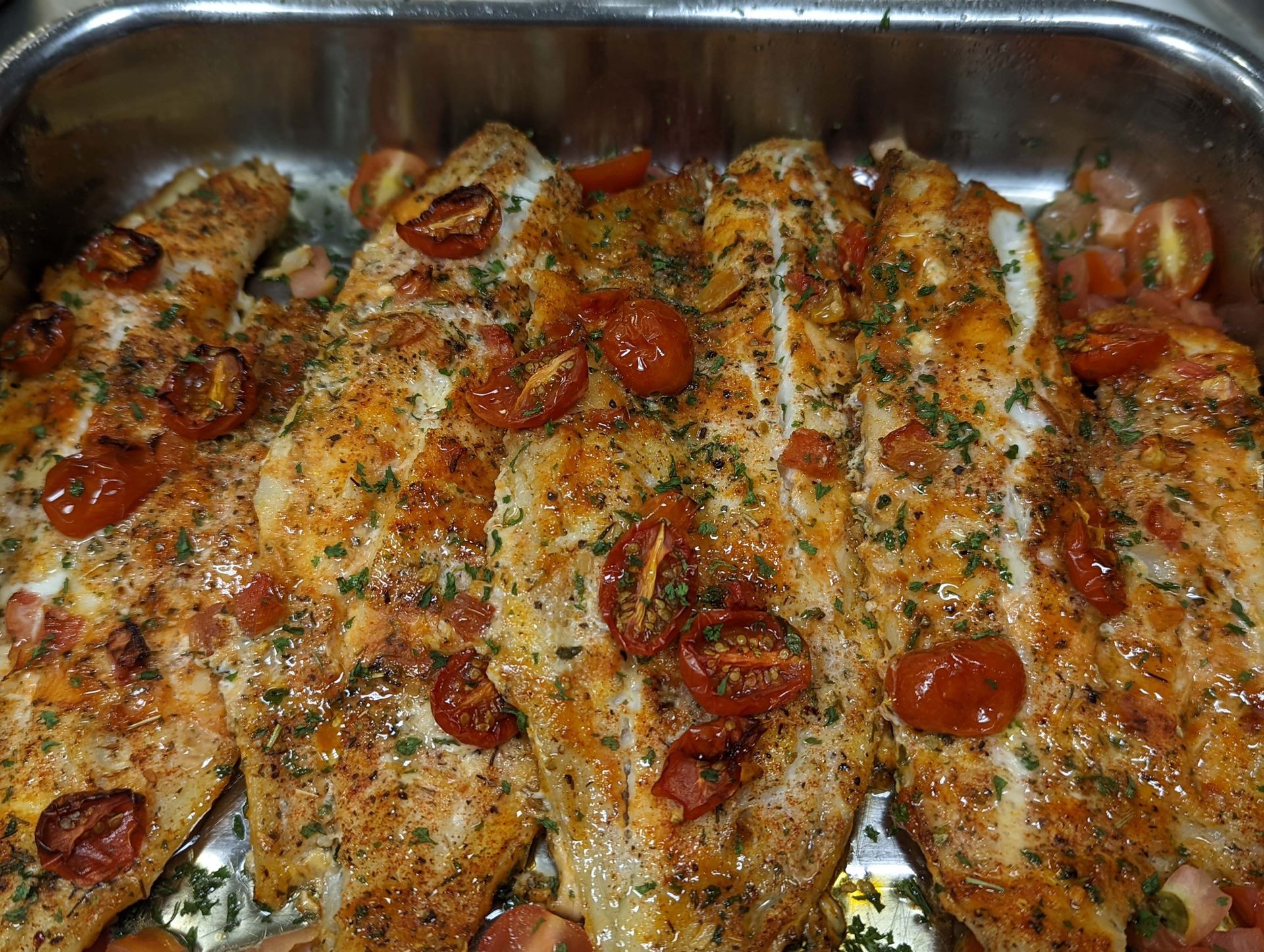 A pan filled with chicken and tomatoes is sitting on a table.
