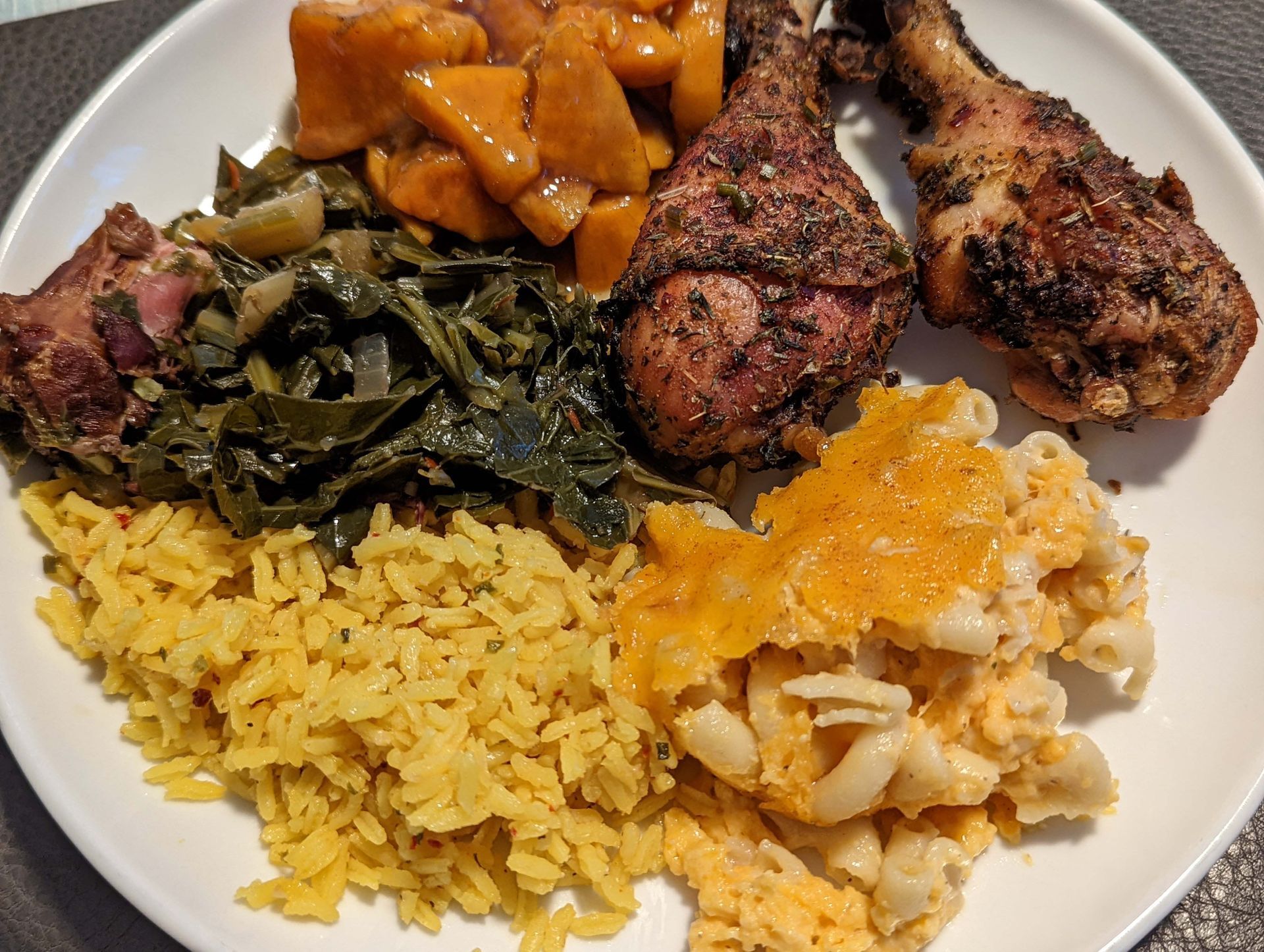 A white plate topped with rice , macaroni and cheese , chicken and vegetables.