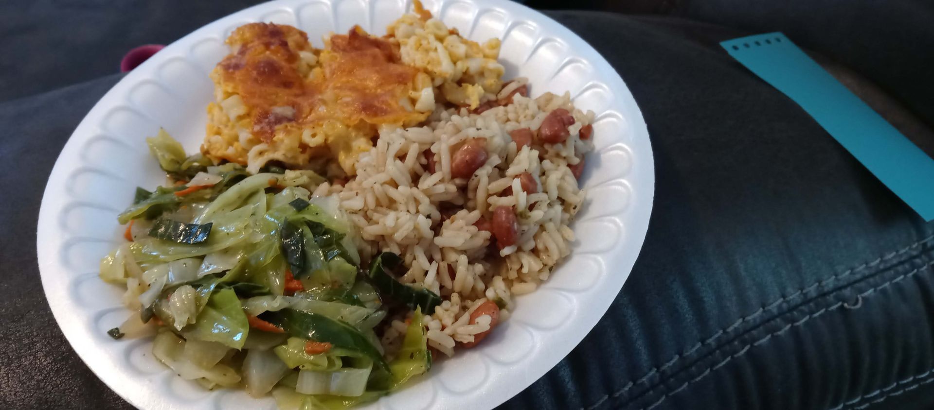 A paper plate topped with rice and vegetables is sitting on a table.