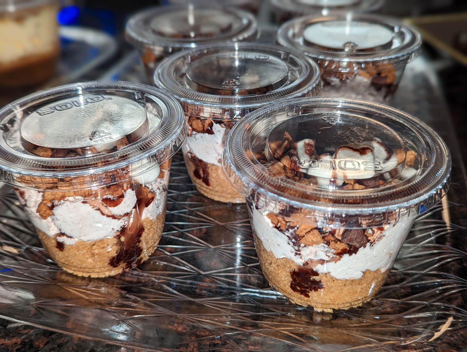 A tray of desserts in plastic cups on a table.
