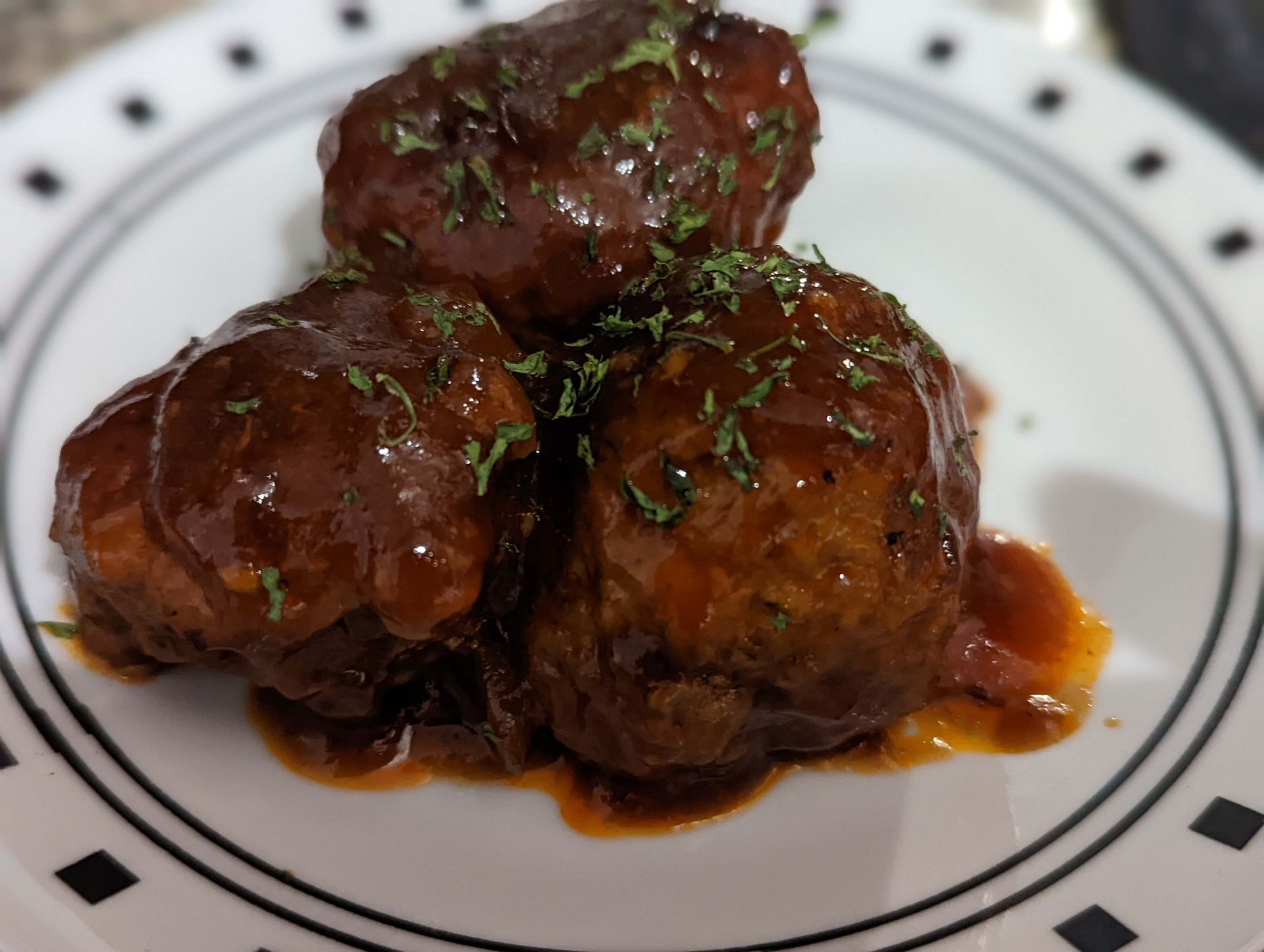 A white plate topped with meatballs and sauce