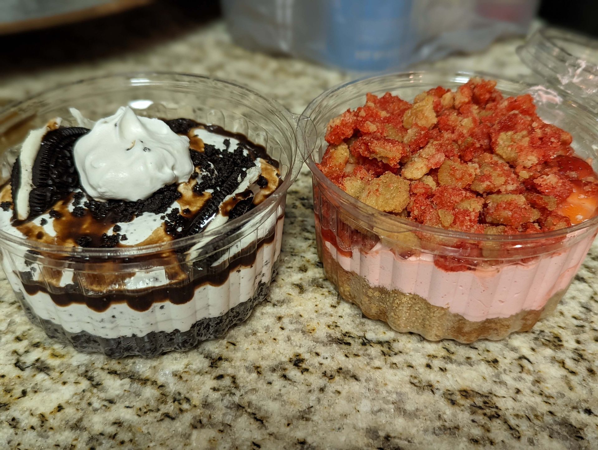 Two desserts in plastic cups are sitting on a counter.