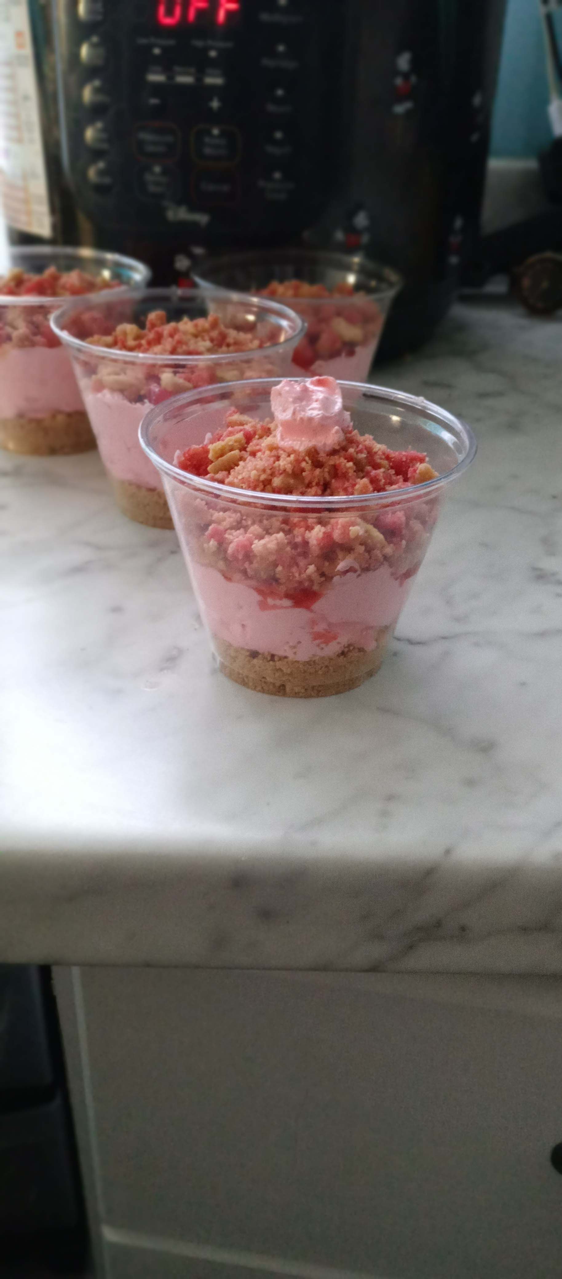 Three cups of dessert are sitting on a counter.