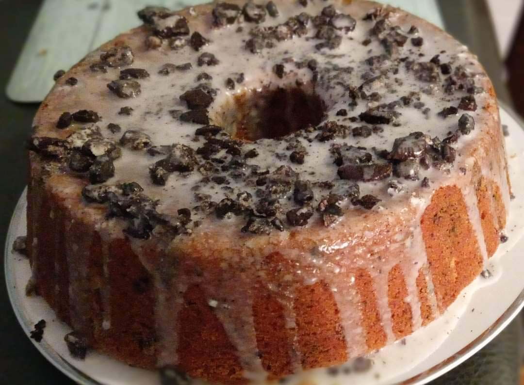 A bundt cake with chocolate chips and icing on a plate.