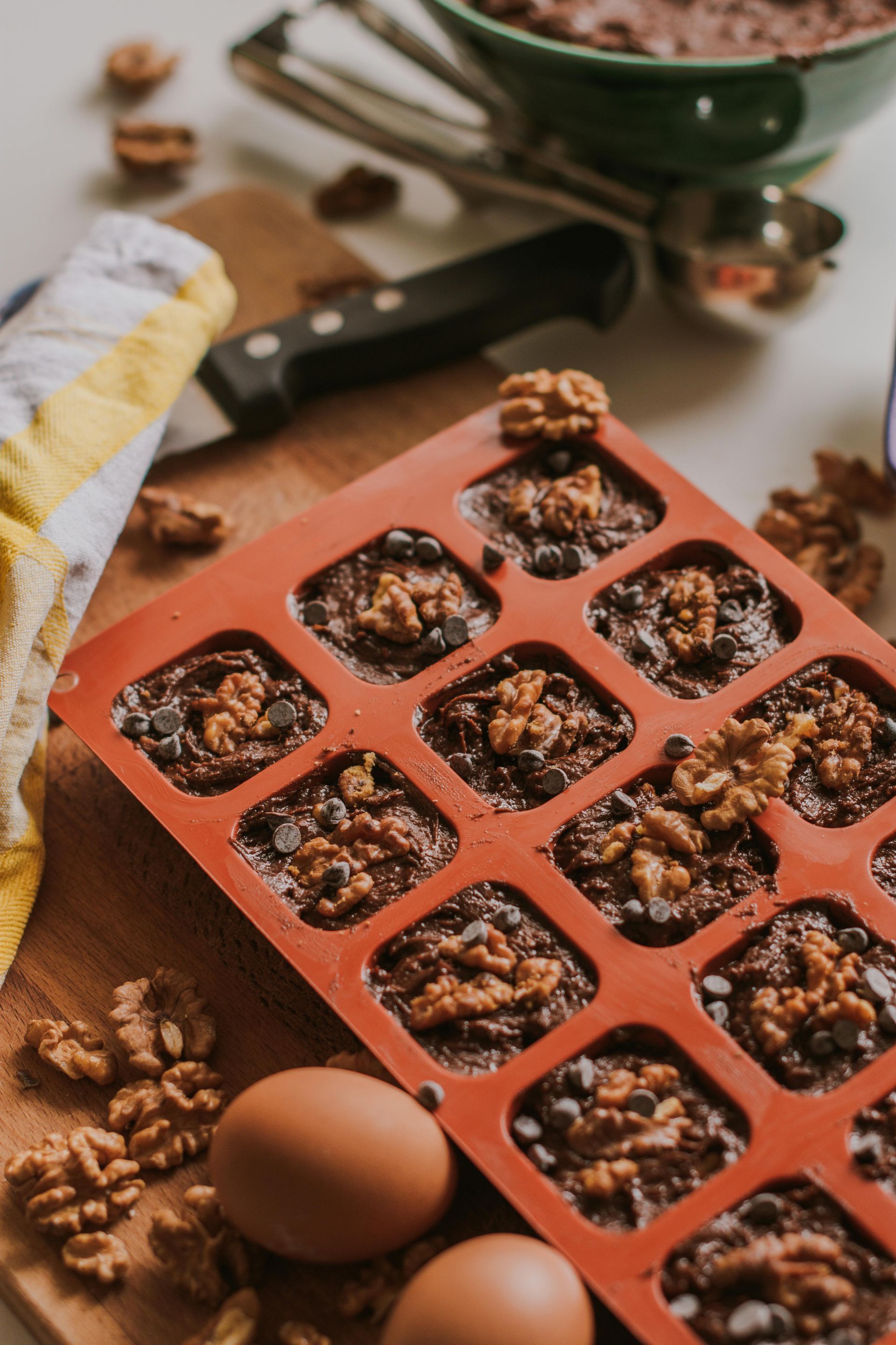 A silicone mould filled with brownies and walnuts on a table.