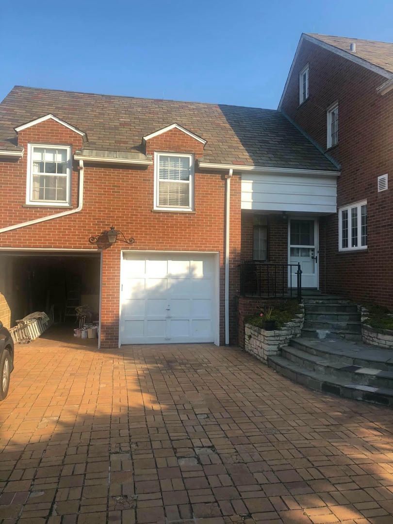 A brick house with a white garage door and a car parked in front of it.