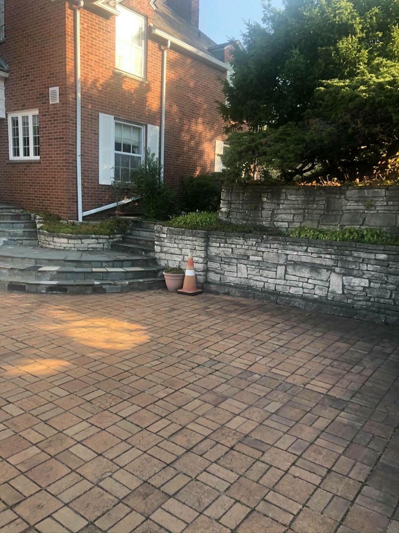 There is a brick driveway in front of a brick house.
