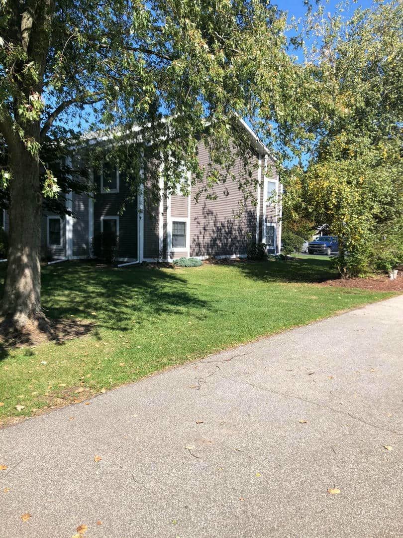 A house with a lot of grass and trees in front of it.