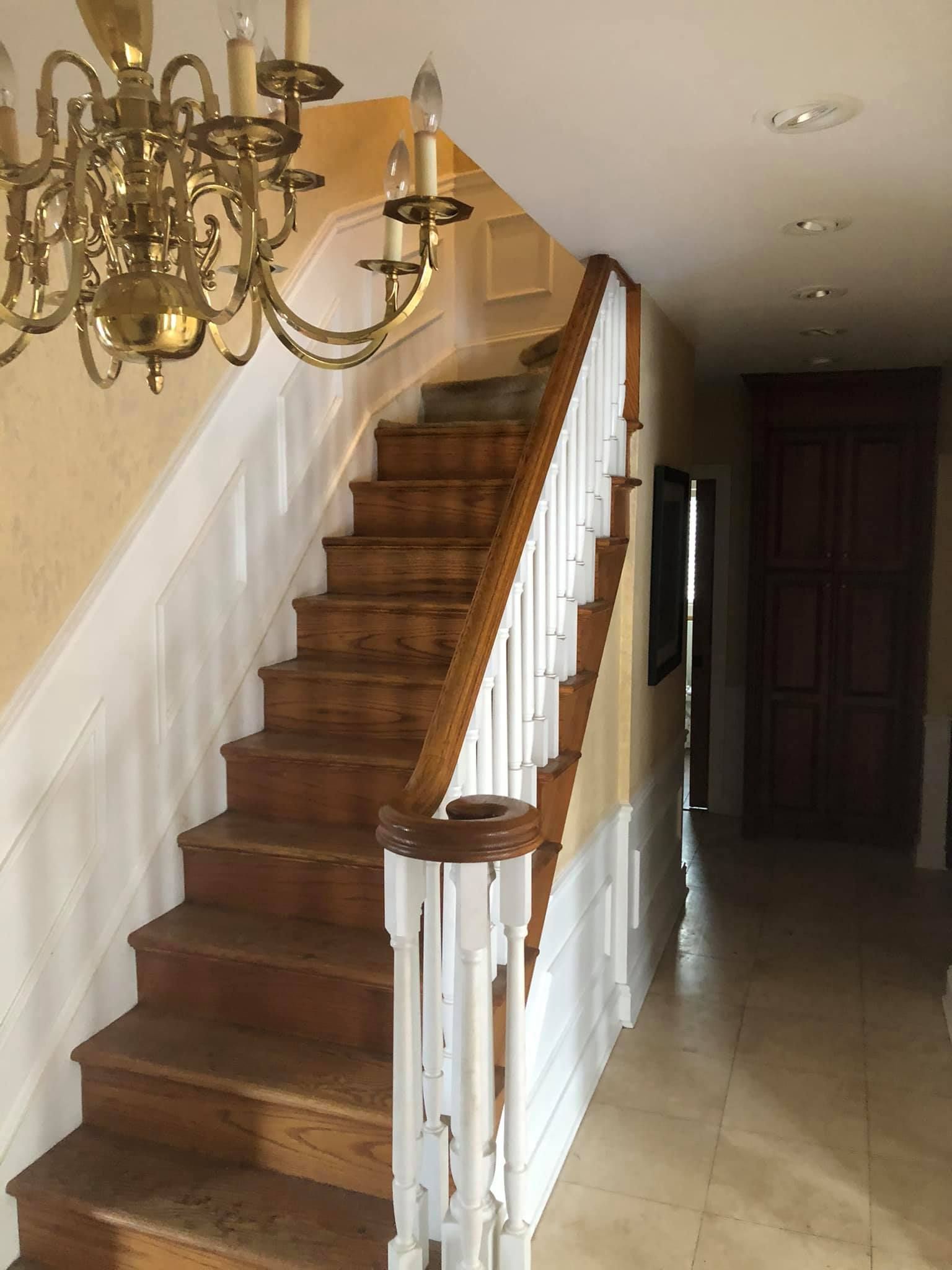 A wooden staircase with white railings and a chandelier hanging from the ceiling