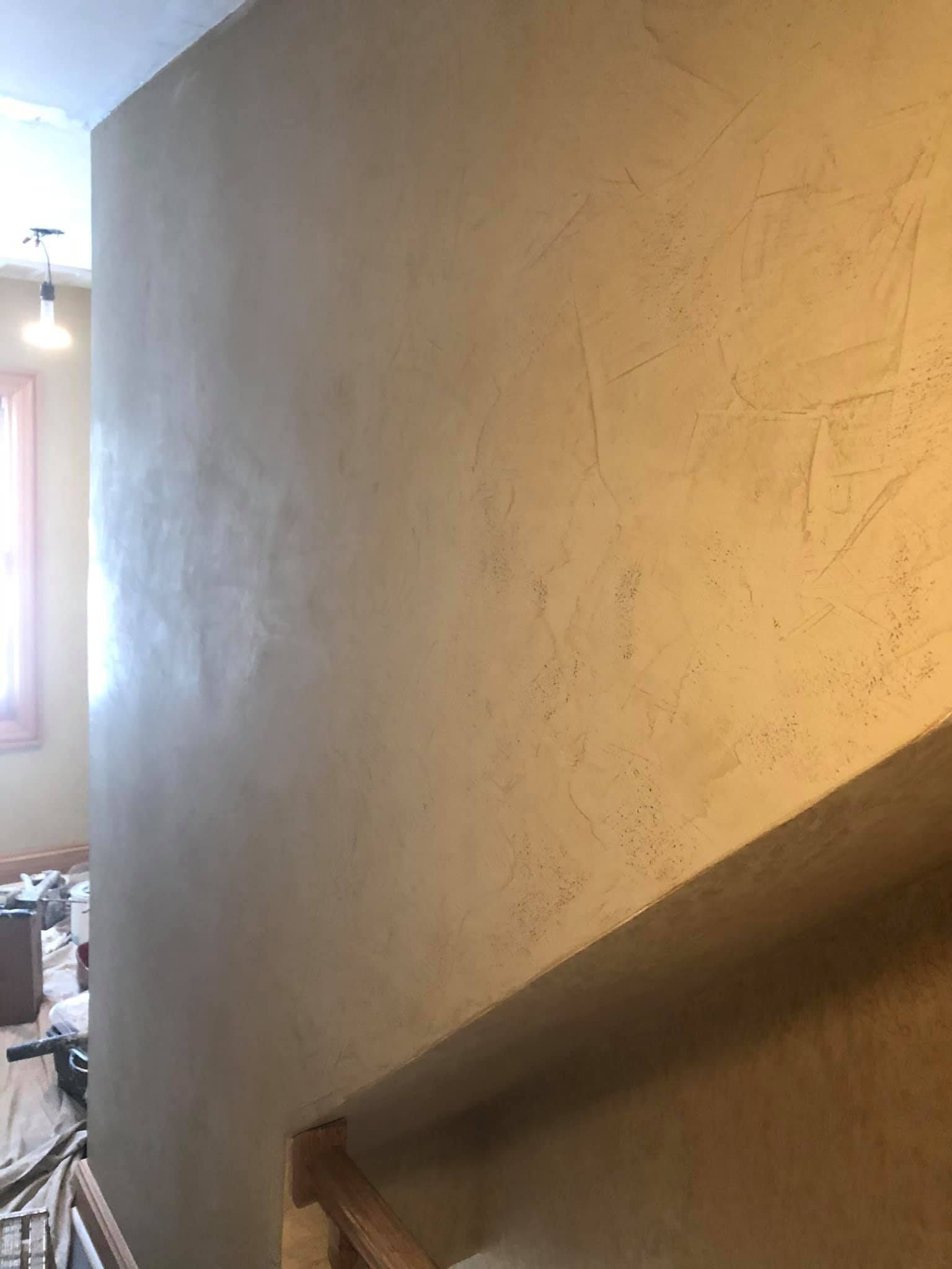 A staircase with a wooden railing and a wall behind it.