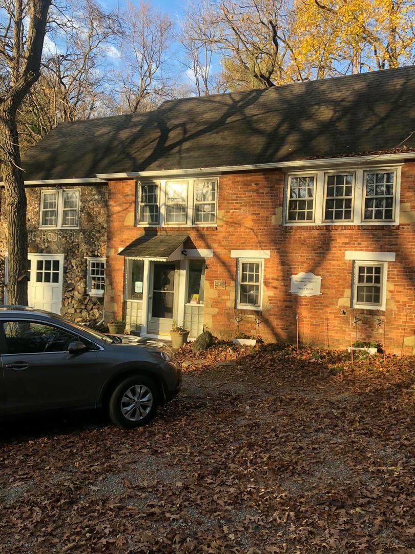 A car is parked in front of a large brick house.