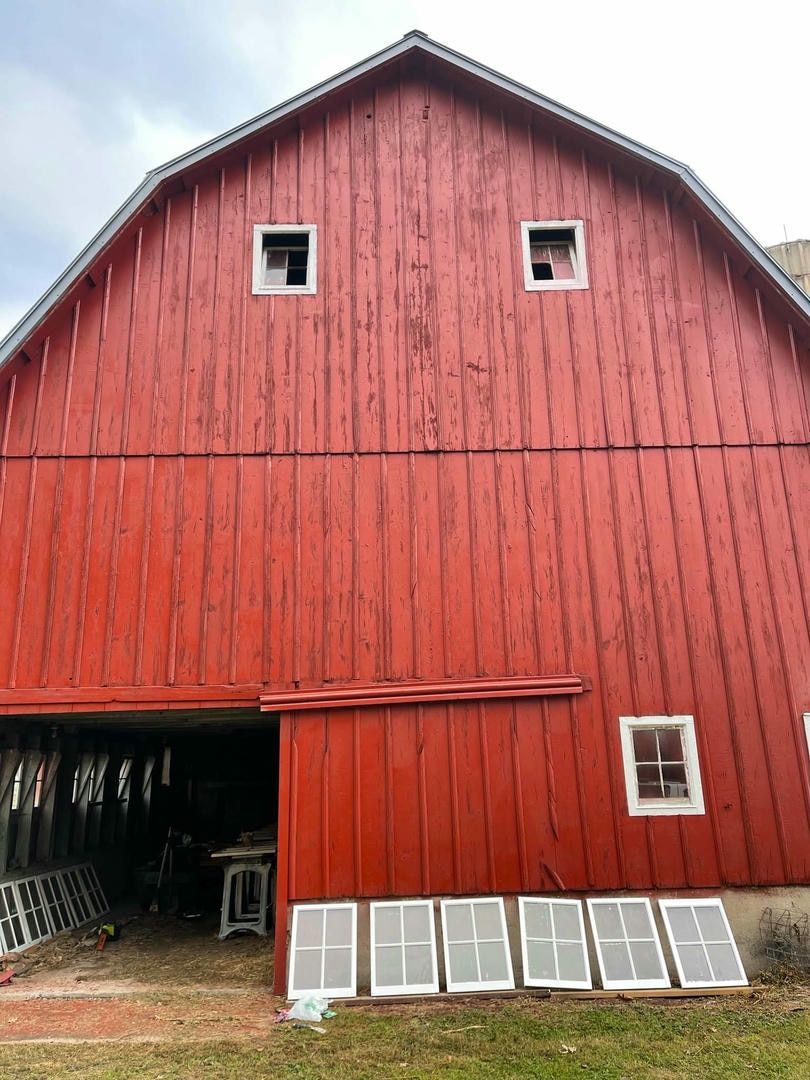A large red barn with a sliding barn door and windows.