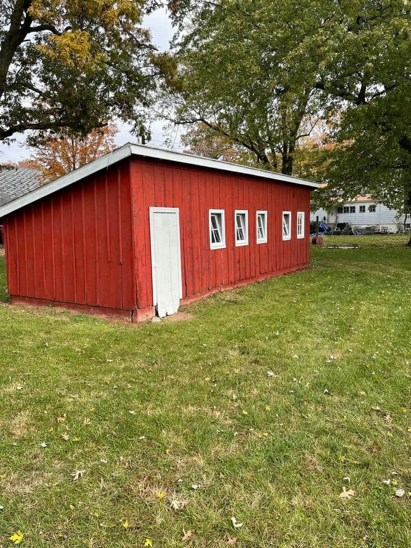 A red barn is sitting in the middle of a grassy field.
