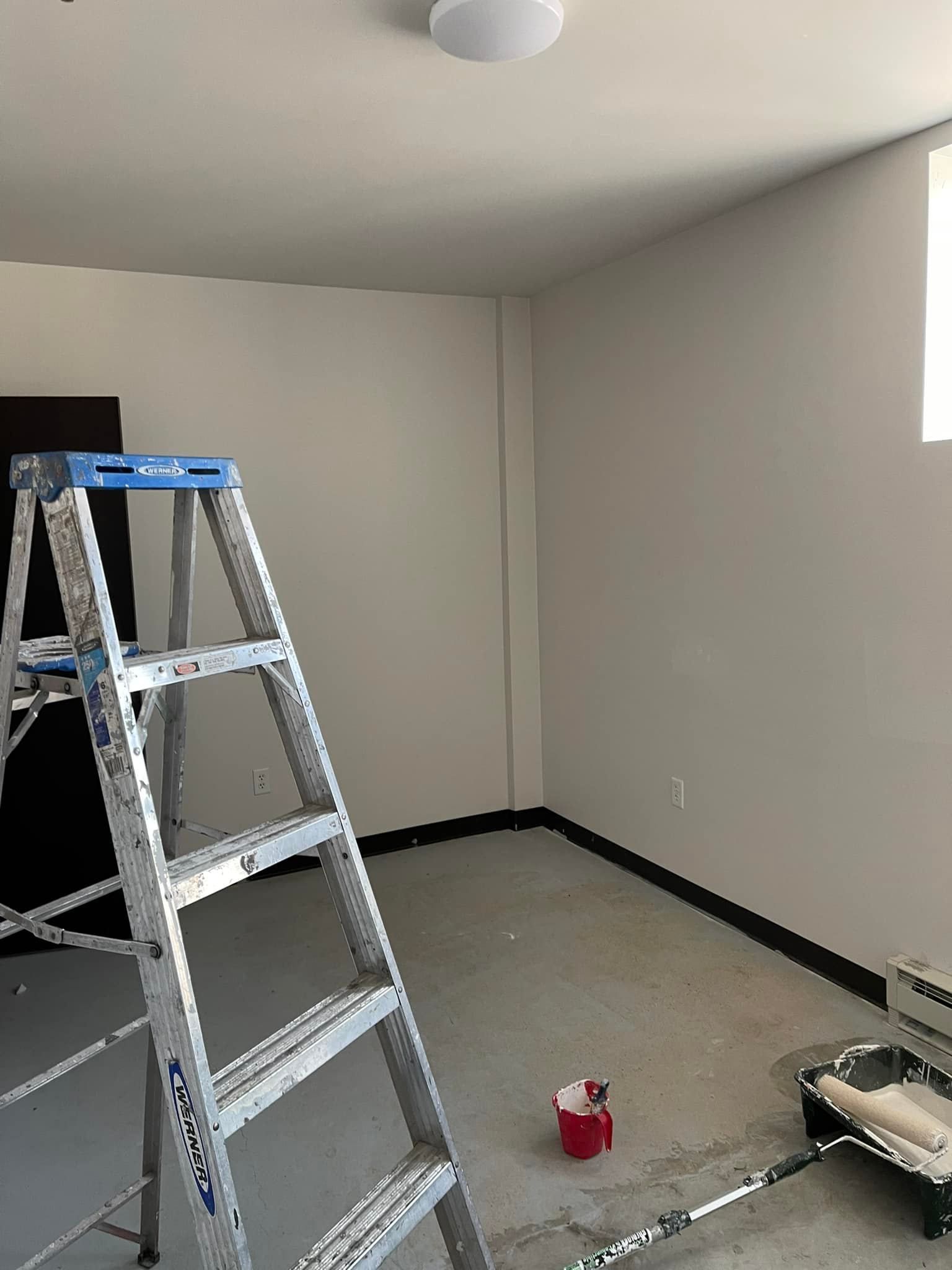 A room with a ladder and a paint roller in it.