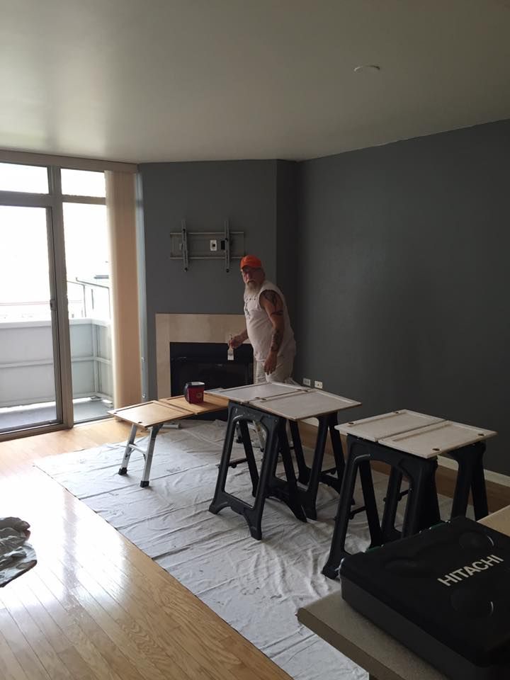 A Man Is Painting A Wall In A Living Room